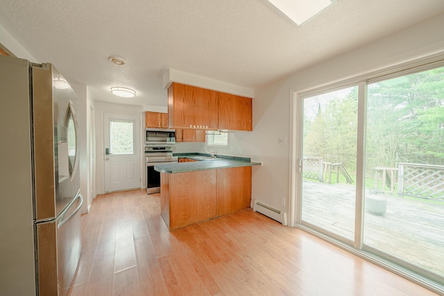452 Moosehead Trl, Waldo, ME 04915 - kitchen featuring appliances with stainless steel finishes, a baseboard radiator, a peninsula, a sink, and light wood-style flooring