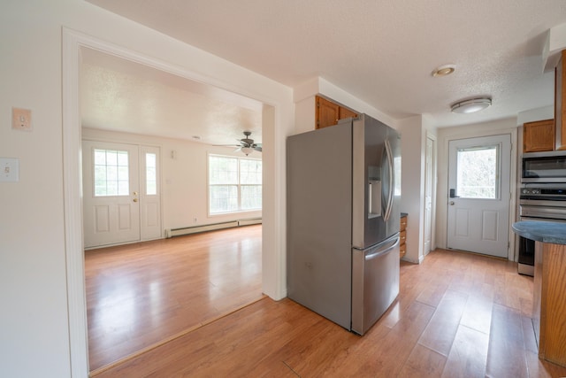 452 Moosehead Trl, Waldo, ME 04915 - kitchen featuring stainless steel appliances, a baseboard heating unit, light wood-type flooring, brown cabinetry, and ceiling fan