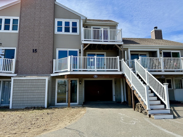 view of building exterior with stairs, an attached garage, and aphalt driveway