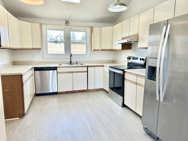 kitchen with light countertops, a sink, light wood-style flooring, under cabinet range hood, and stainless steel appliances