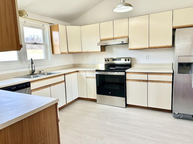 kitchen with vaulted ceiling, light countertops, a sink, under cabinet range hood, and stainless steel appliances