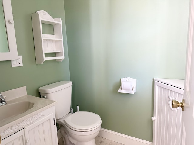 half bathroom with toilet, vanity, and baseboards