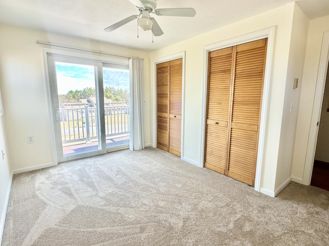 unfurnished bedroom featuring baseboards, access to exterior, two closets, and carpet floors