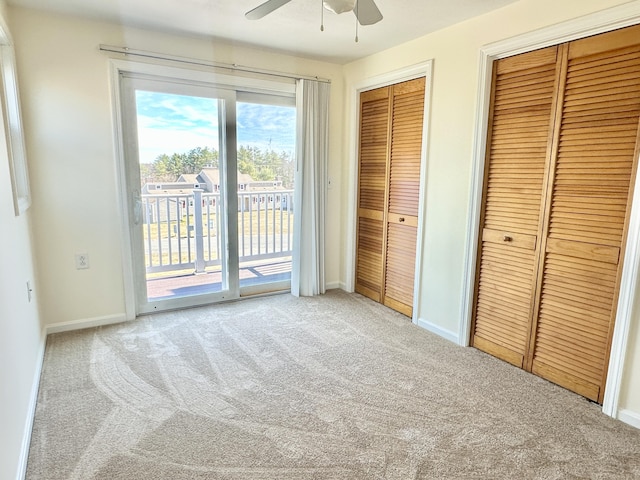 unfurnished bedroom with carpet flooring, multiple closets, baseboards, access to outside, and a ceiling fan