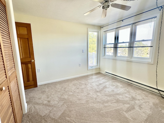 empty room with carpet flooring, a textured ceiling, a baseboard heating unit, baseboards, and ceiling fan