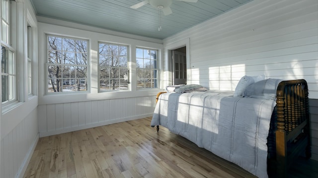 sunroom / solarium with wood finished floors, a healthy amount of sunlight, and a ceiling fan