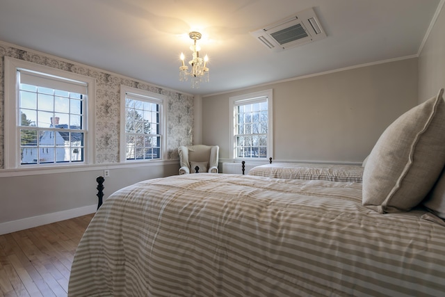 bedroom featuring baseboards, a chandelier, crown molding, and wood-type flooring