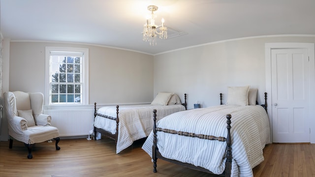 bedroom with radiator heating unit, ornamental molding, a chandelier, and wood finished floors