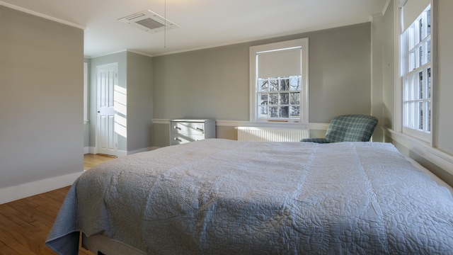 bedroom featuring radiator, visible vents, wood finished floors, and ornamental molding
