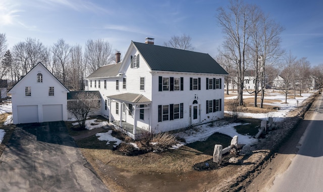 colonial inspired home featuring metal roof, aphalt driveway, and a chimney