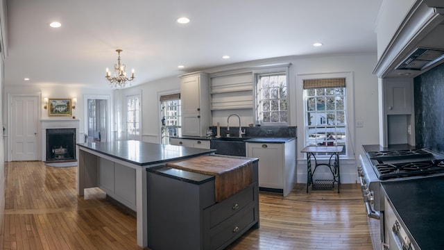 kitchen featuring ventilation hood, open shelves, high end stove, gray cabinetry, and hardwood / wood-style floors