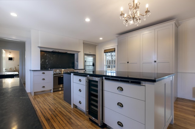 kitchen featuring high end appliances, a kitchen island, beverage cooler, light wood-style flooring, and white cabinets