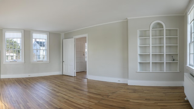 empty room featuring baseboards, wood finished floors, and crown molding