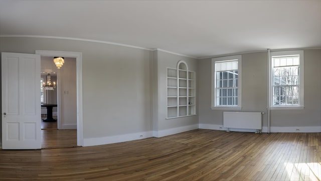 unfurnished room featuring hardwood / wood-style flooring, a chandelier, crown molding, and radiator