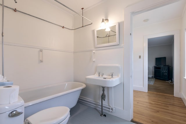 full bathroom with a soaking tub, toilet, ornamental molding, and wood finished floors