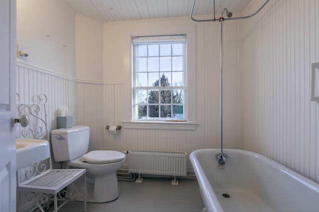full bath featuring a soaking tub, toilet, radiator, and a healthy amount of sunlight