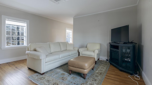 living room with a wealth of natural light, visible vents, ornamental molding, and wood finished floors