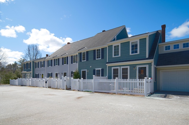 view of front of property with a garage, a fenced front yard, and a chimney