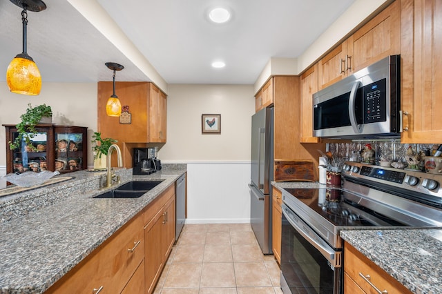 kitchen with brown cabinetry, a sink, and stainless steel appliances