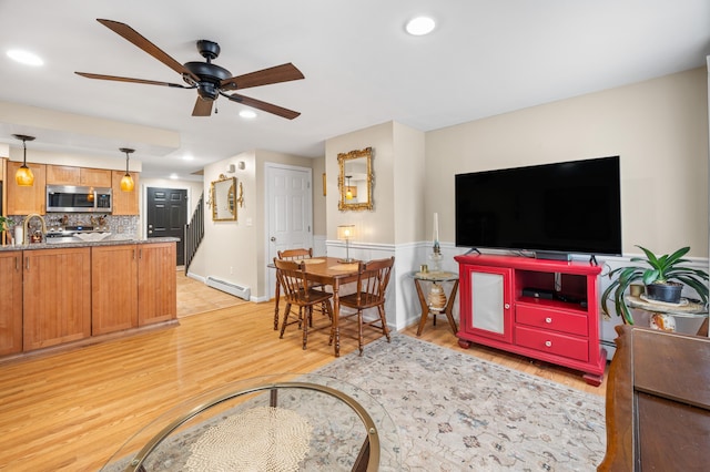 living room with a baseboard radiator, light wood-style flooring, recessed lighting, and a ceiling fan