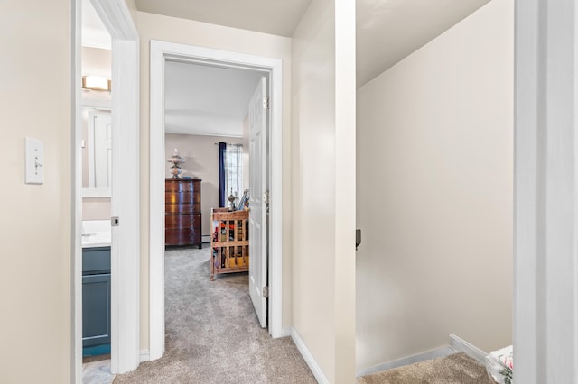 corridor featuring baseboards and light colored carpet