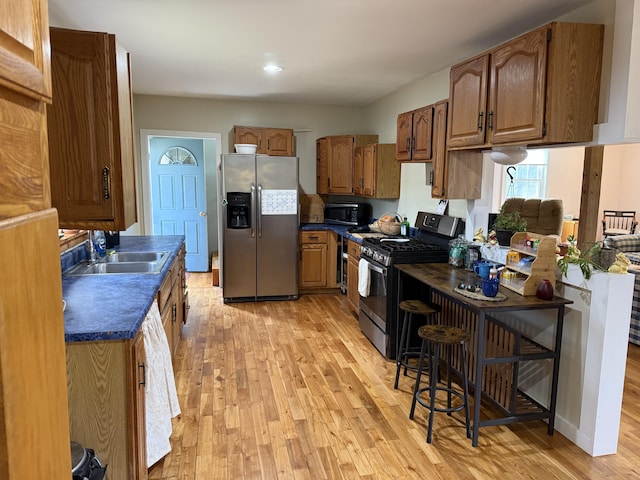 148 Pendleton Point Rd, Islesboro, ME 04848 - kitchen with appliances with stainless steel finishes, light wood-type flooring, dark countertops, a sink, and brown cabinets