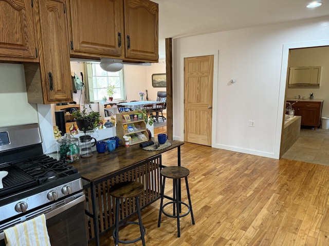 148 Pendleton Point Rd, Islesboro, ME 04848 - kitchen featuring stainless steel gas range oven, light wood-style flooring, brown cabinetry, and baseboards