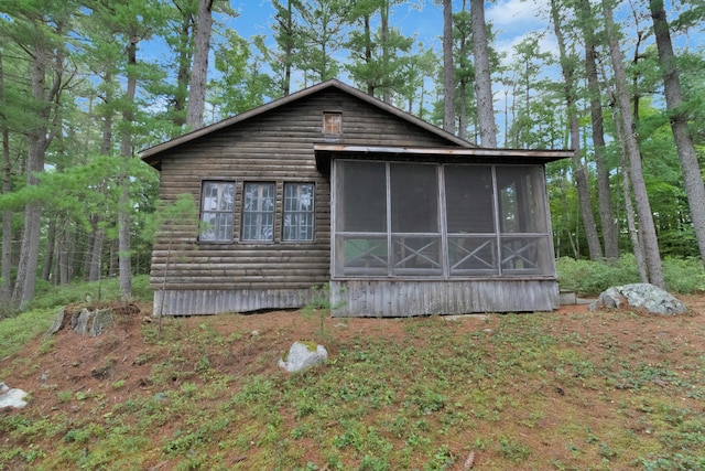 back of house featuring a sunroom and faux log siding
