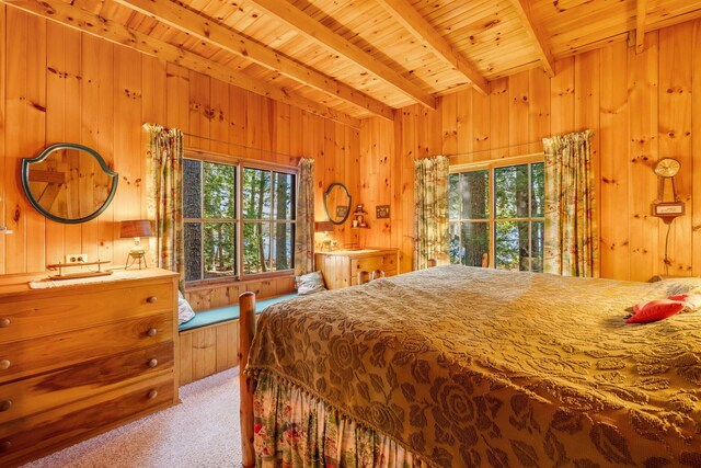 bedroom with beam ceiling, carpet flooring, multiple windows, wood walls, and wooden ceiling