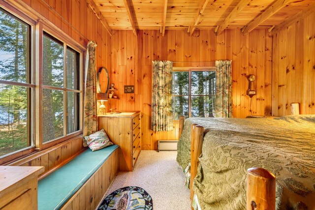 bedroom with a baseboard radiator, beamed ceiling, wooden walls, carpet, and wood ceiling