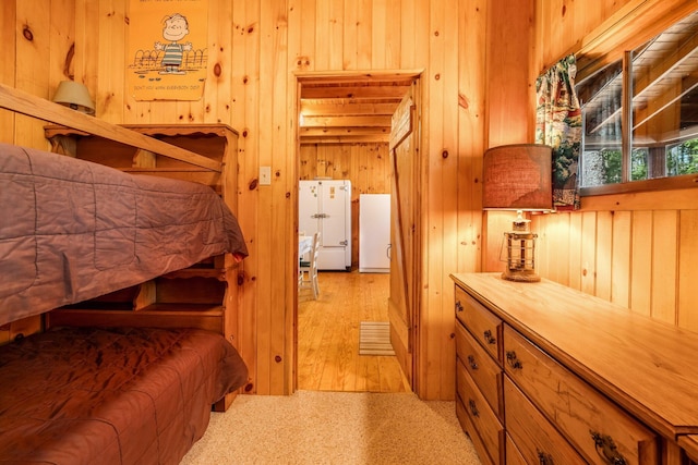 bedroom featuring wood walls and freestanding refrigerator