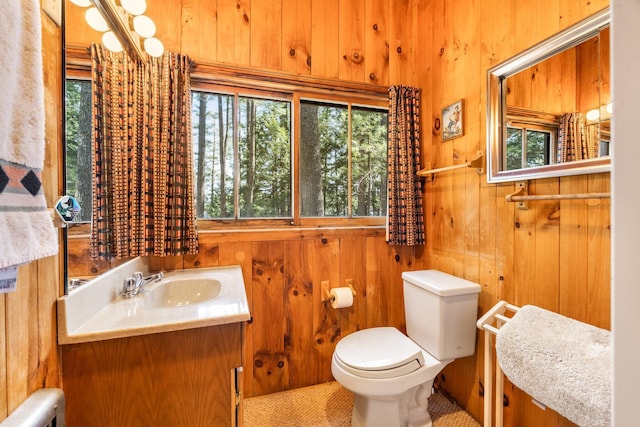 half bathroom featuring toilet, wooden walls, vanity, and radiator heating unit