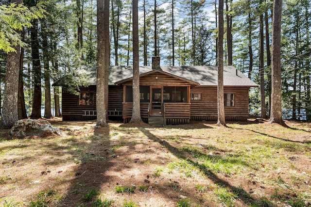 back of house featuring a chimney, a sunroom, and faux log siding