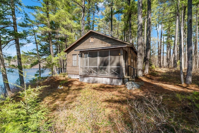 back of property with a sunroom, faux log siding, and a water view