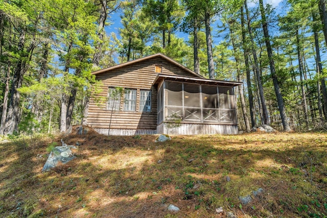 view of front of home featuring a sunroom and faux log siding