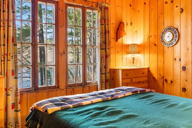bedroom featuring wood walls and multiple windows