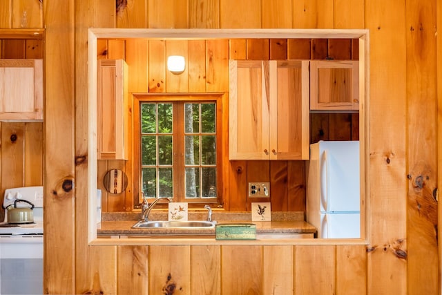 kitchen featuring a sink, white appliances, wood walls, and light countertops