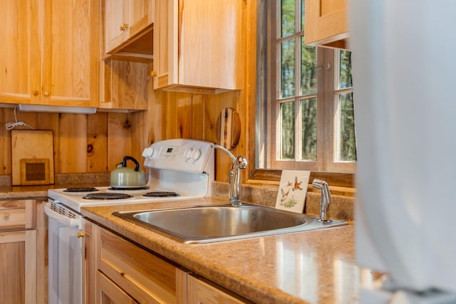 kitchen with white electric stove, light countertops, refrigerator, and a sink