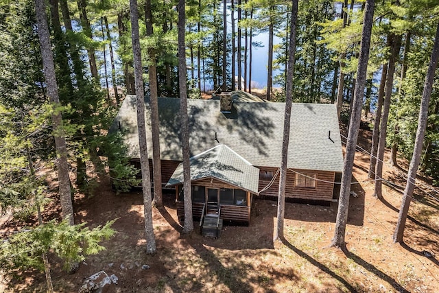 rear view of property with roof with shingles and faux log siding