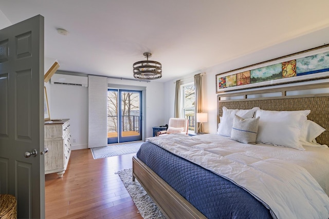 bedroom featuring hardwood / wood-style flooring, an AC wall unit, baseboards, and a notable chandelier