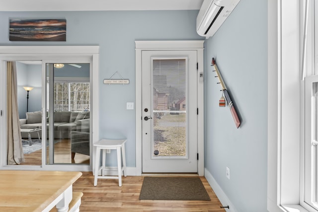 doorway featuring an AC wall unit, baseboards, and light wood-type flooring