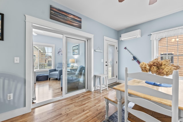 bedroom featuring a wall mounted AC, wood finished floors, access to outside, baseboards, and ceiling fan