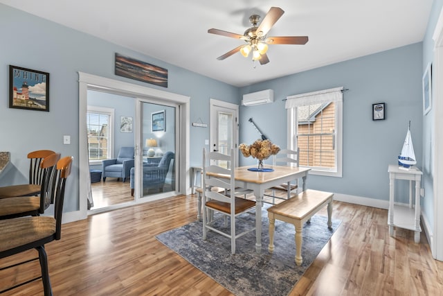 dining area with a wall mounted AC, baseboards, ceiling fan, and light wood-type flooring