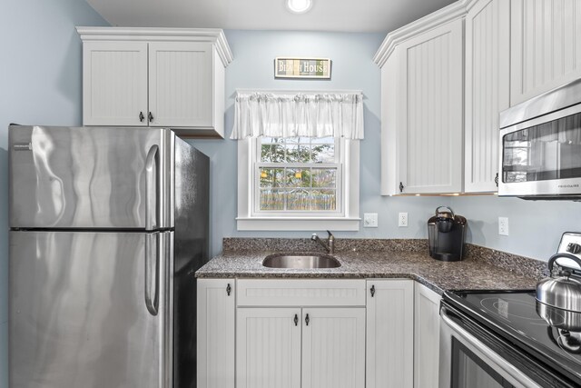 kitchen featuring a sink, white cabinetry, dark stone countertops, and appliances with stainless steel finishes