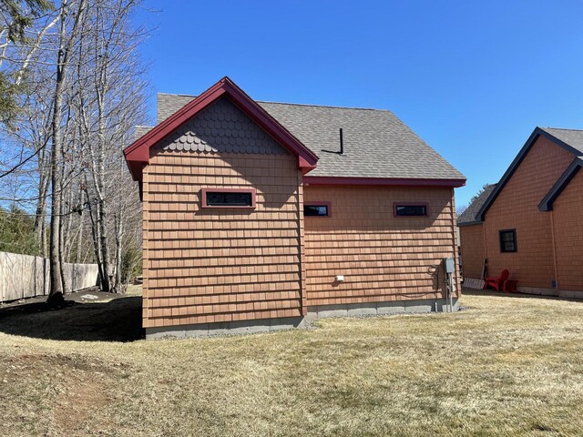back of property with a lawn, a shingled roof, and fence