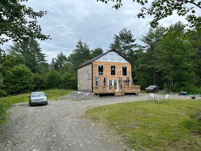 view of front facade with driveway, a wooden deck, and a front yard