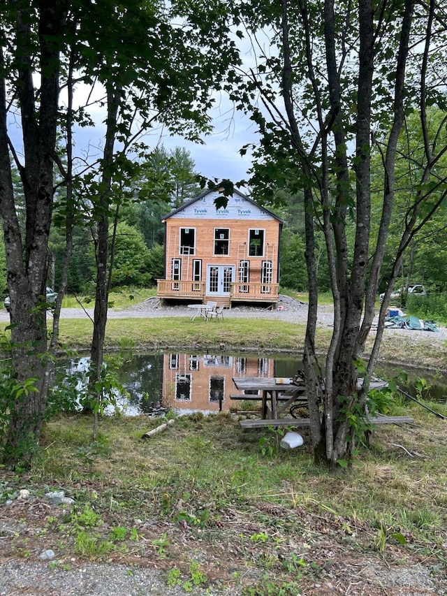 back of house with an outdoor structure and a deck with water view