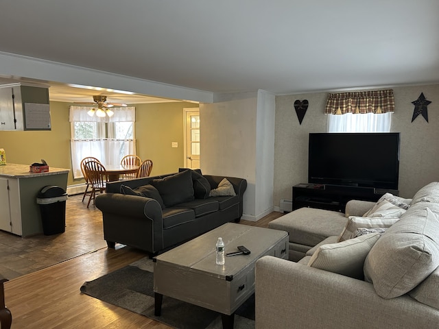 living room featuring ceiling fan, a baseboard heating unit, ornamental molding, and wood finished floors