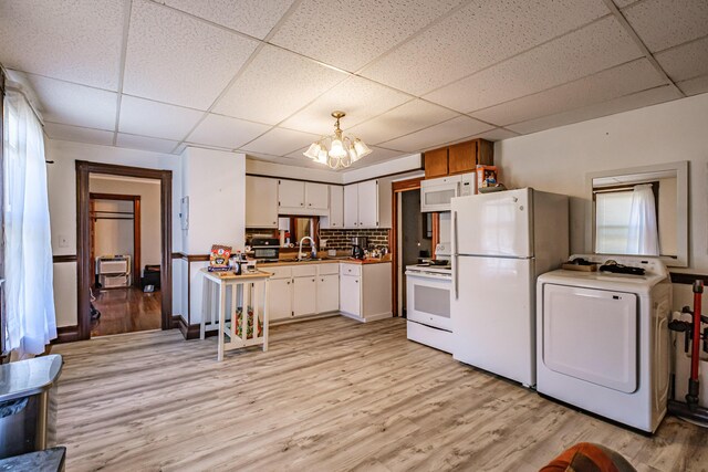 kitchen featuring washer / dryer, white appliances, a paneled ceiling, white cabinets, and light wood finished floors