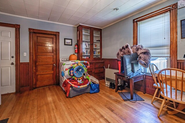 bedroom featuring a wainscoted wall, crown molding, hardwood / wood-style floors, and wood walls